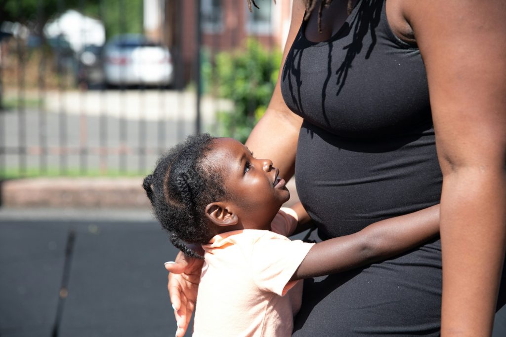 A toddler hugging an expectant mother