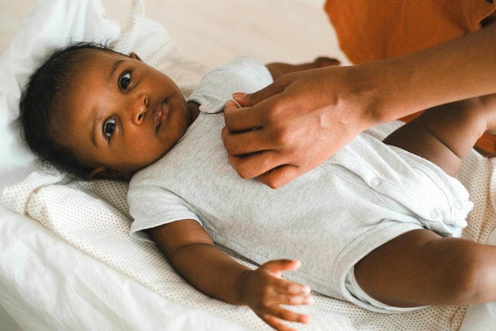 A caregiver gently touching a smiling baby