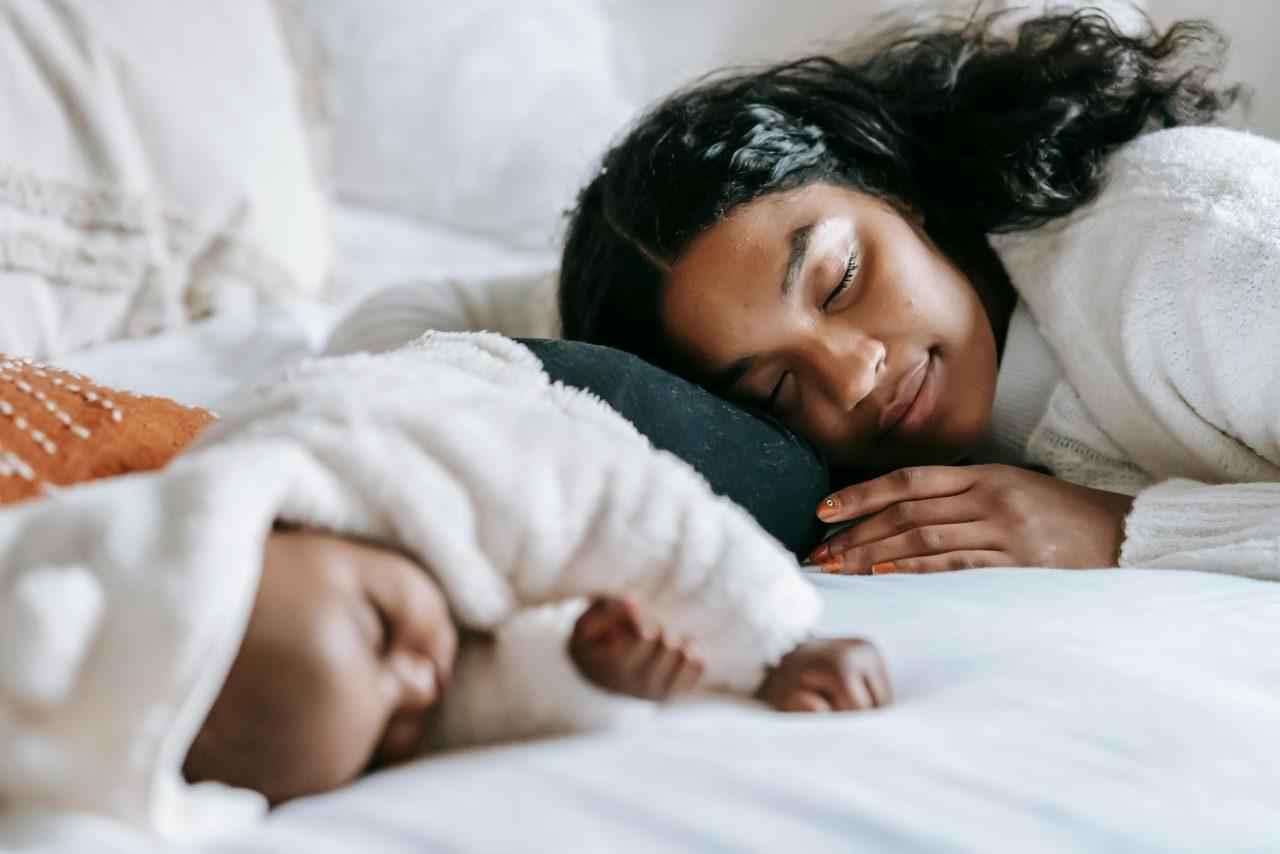 A mother resting beside her sleeping baby